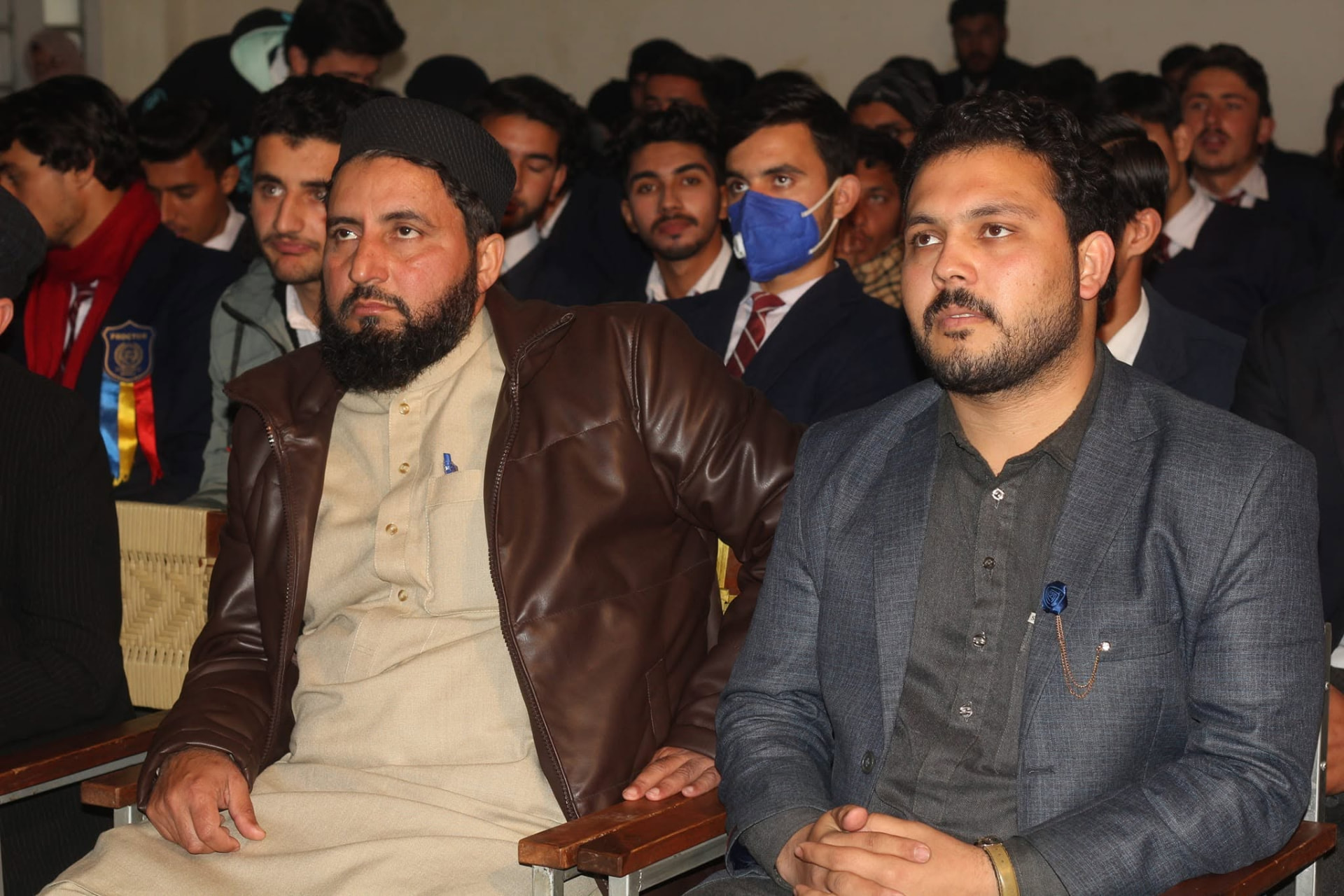 Abdullah Khan seated on stage at a college technology event with students in the audience